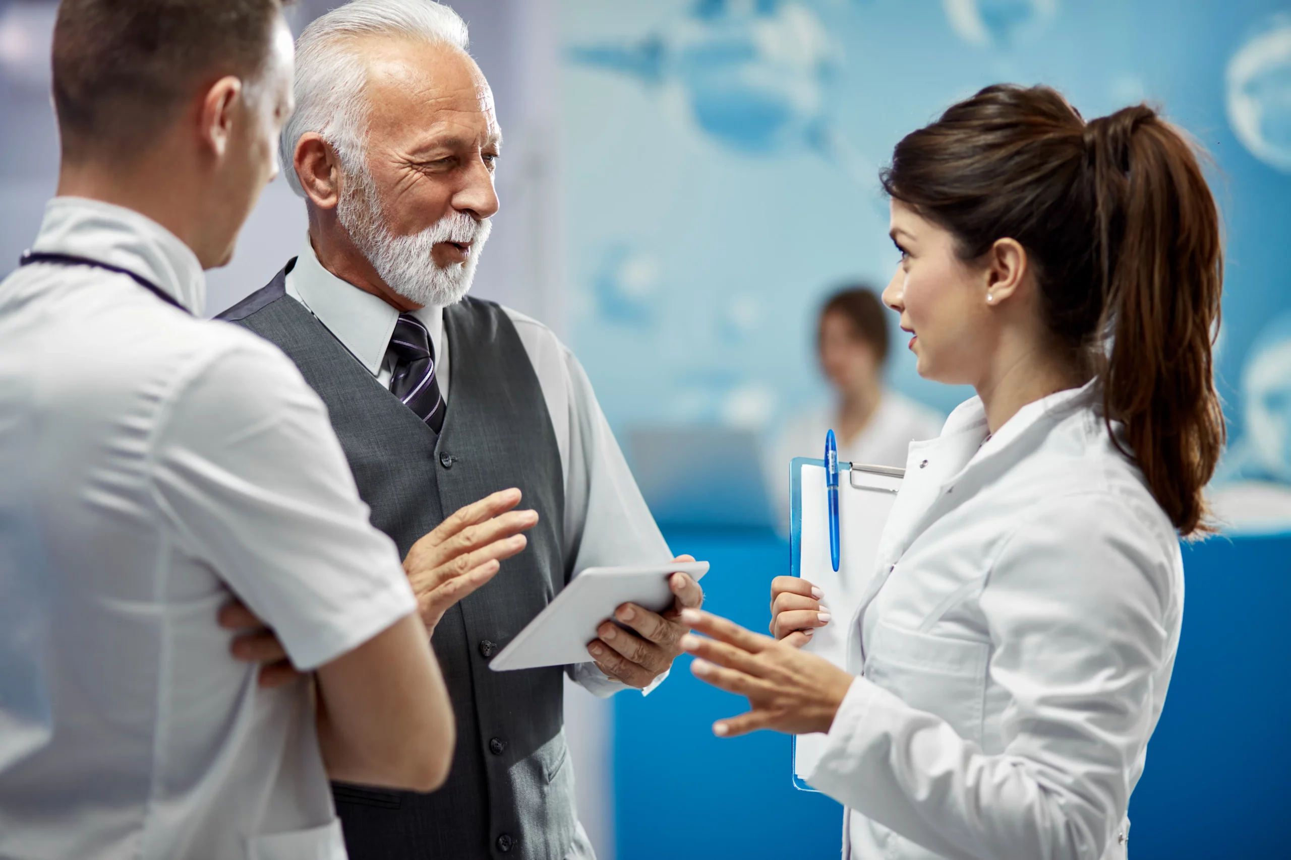 smiling-mature-financial-advisor-doctors-communicating-while-standing-lobby-medical-clinic-scaled